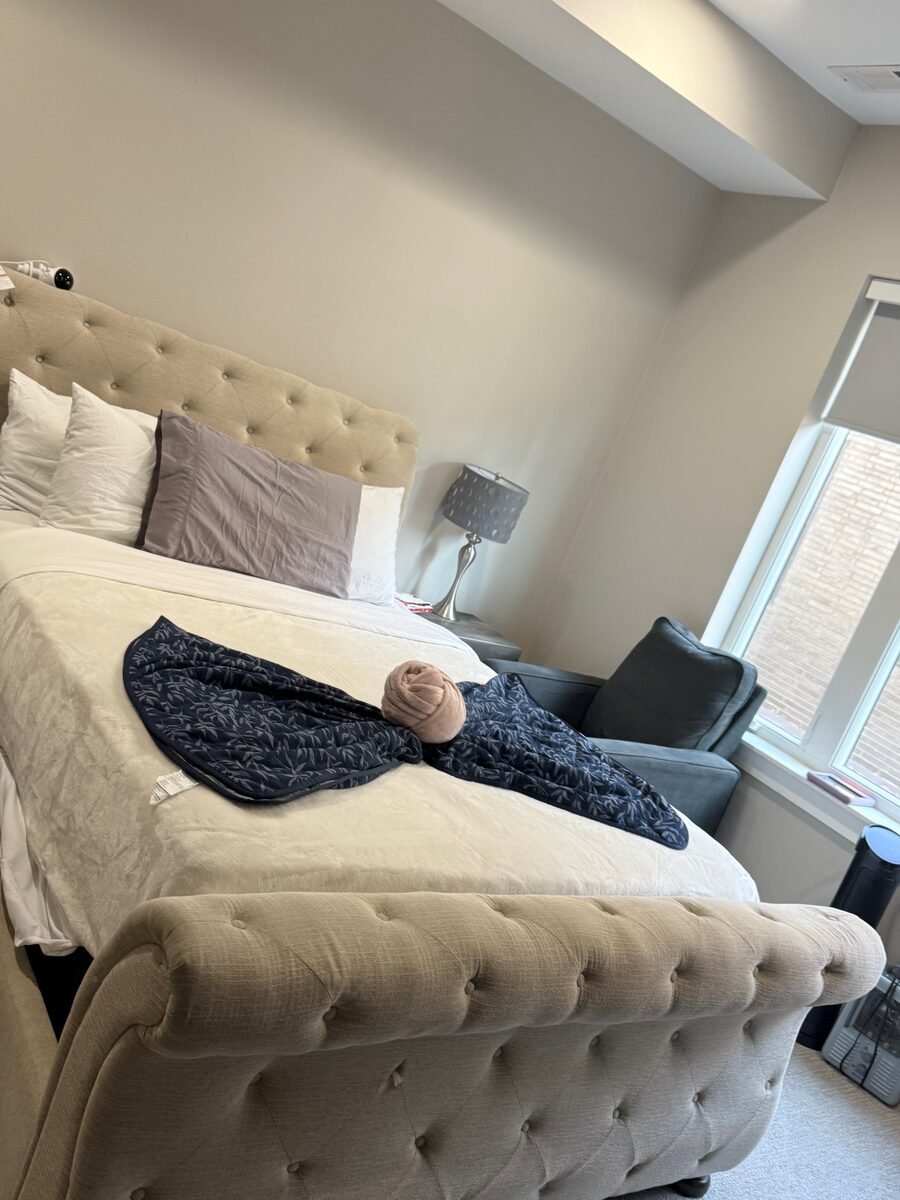 A bed made up with crisp white bedding against a tufted headboard