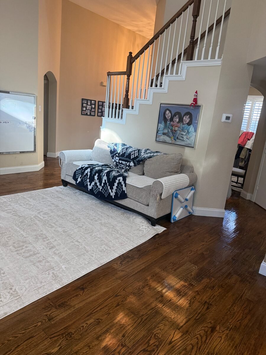 A living room and staircase with the rug vacuumed and surfaces dusted