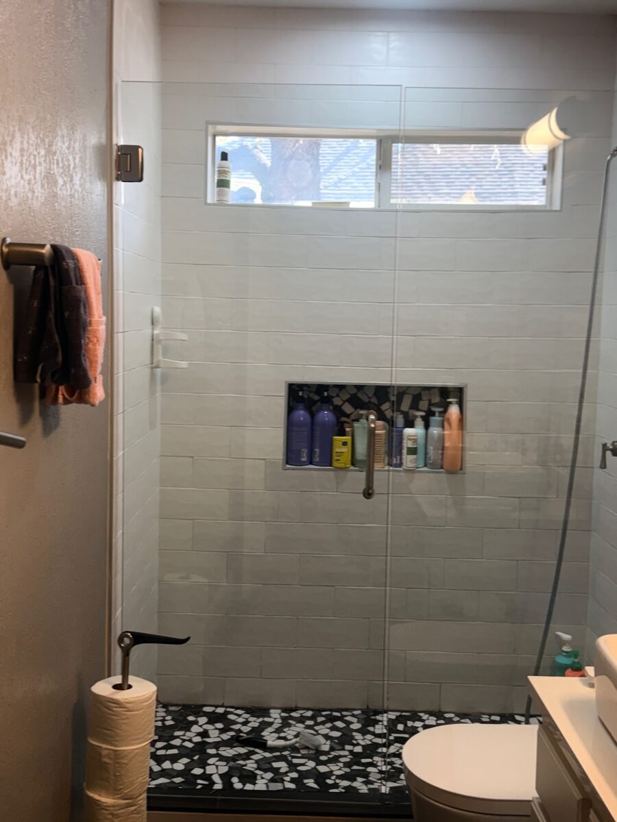A walk-in shower with the tile, glass and pebble floor cleaned